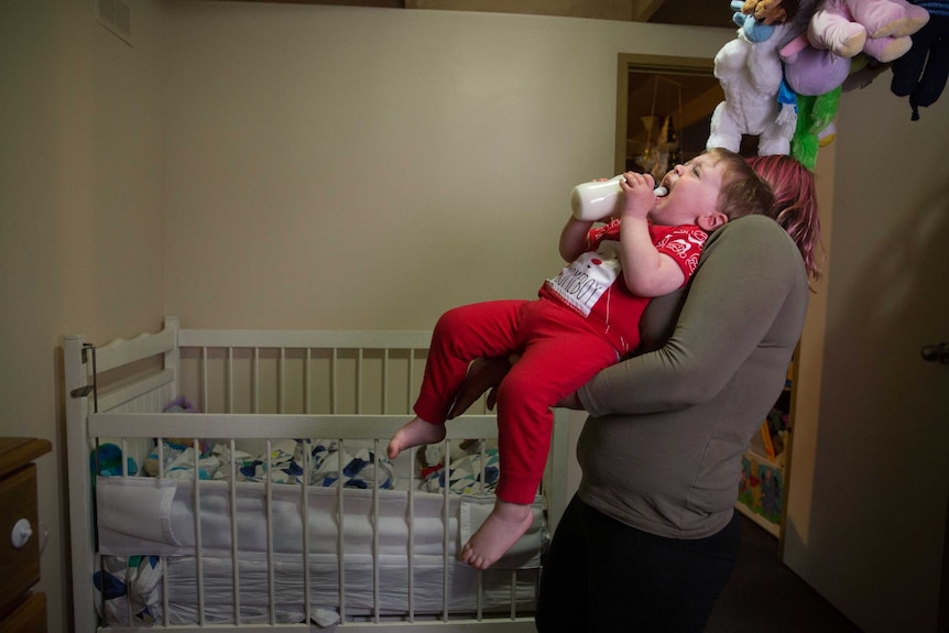 Amber carries a crying Roman to bed.