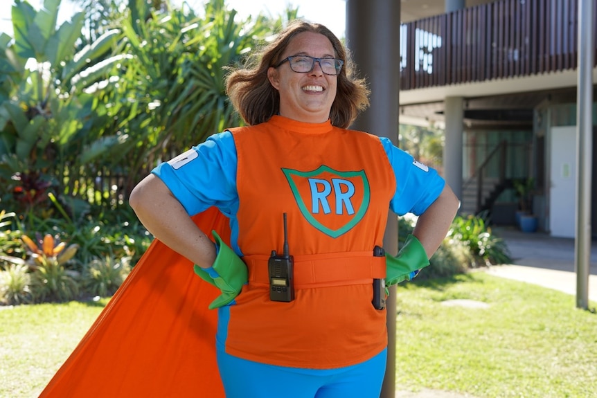 A photo of a woman in a orange and blue superhero outfit with R and R on the front.