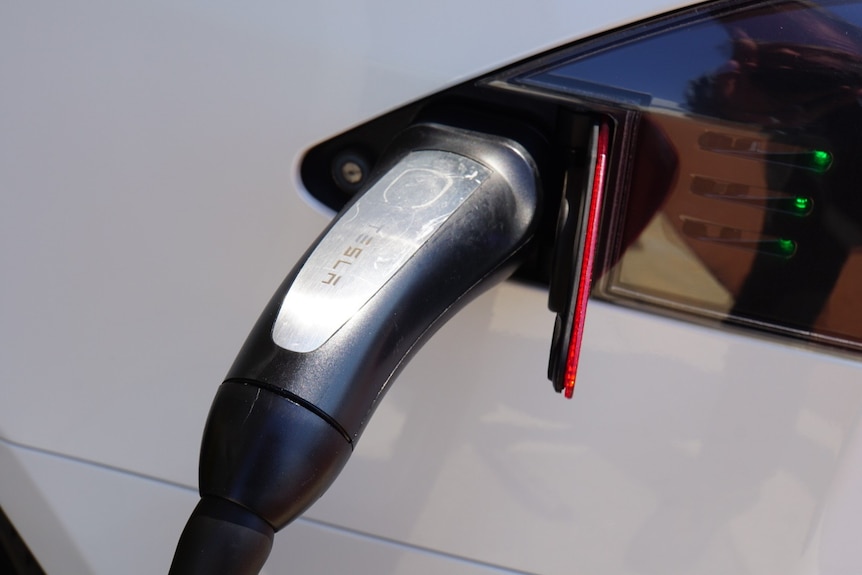 An electric vehicle charger attached to a car.