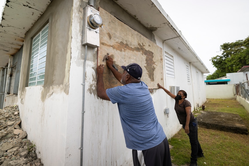 A couple boards up the windows of their home in anticipation of the hurricane. 