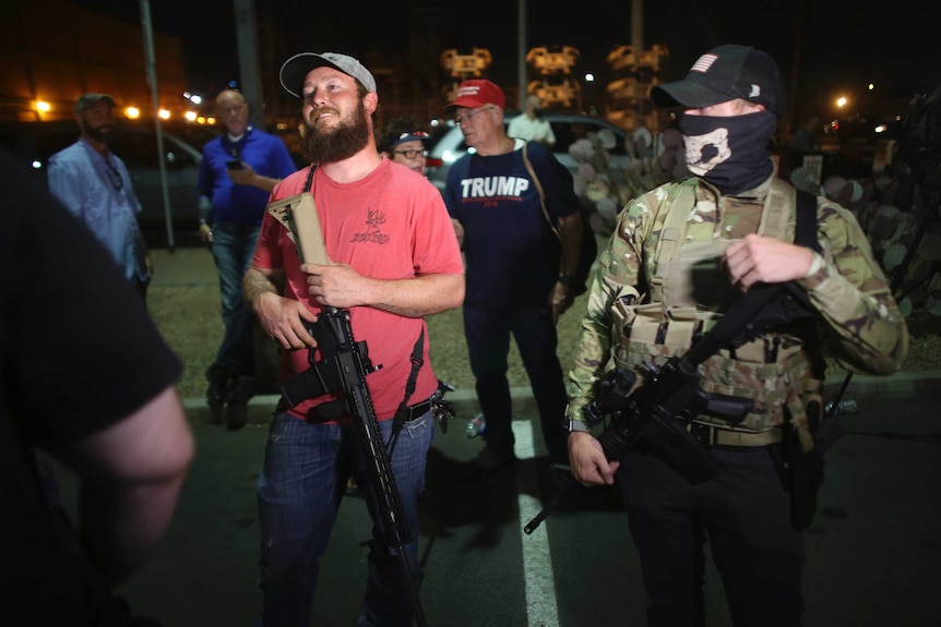 Trump supporters stand with large rifles outside a vote counting facility in Arizona.