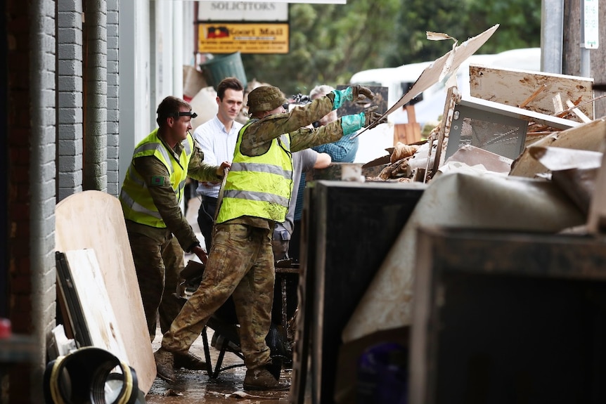 Two defence force members throw rubbish in a skip