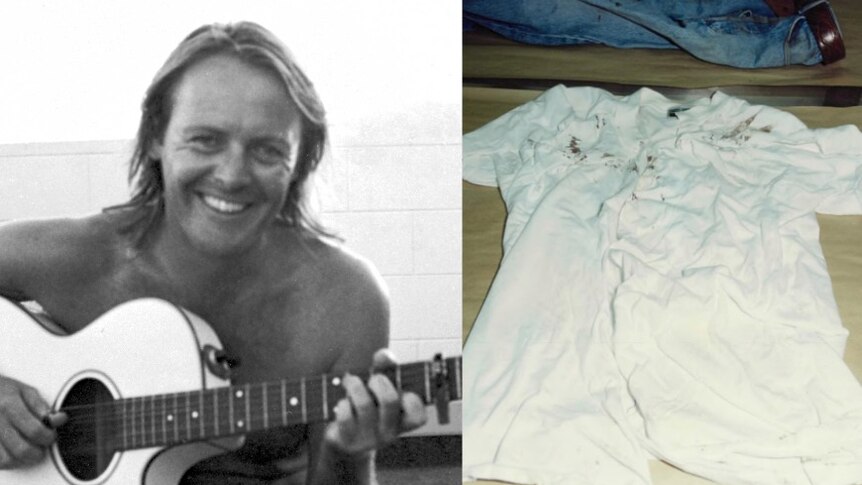 A black and white photo of a man with a guitar and a white shirt with blood stains