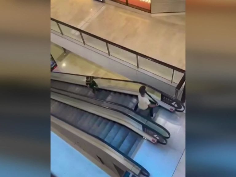 Mobile vision shows a man at the top of an escalator brandishing a bollard as a man approaches him.