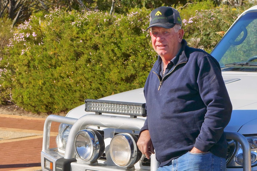 A man looks at the camera leaning on the bullbar of his ute