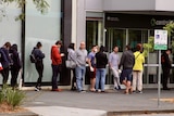 A queue of people stretches down York Street in South Melbourne, starting at the entrance to a Centrelink building.