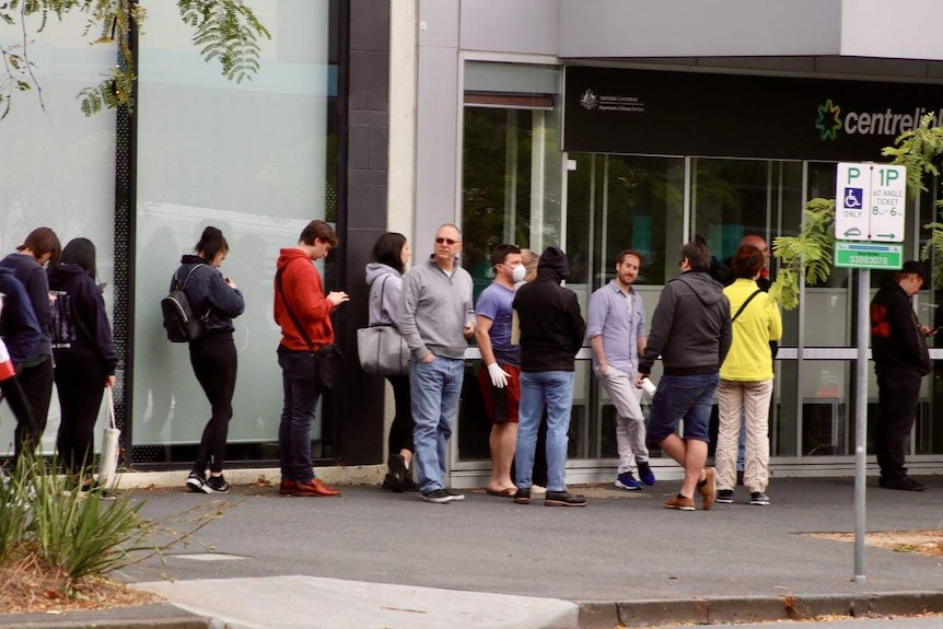 A queue of people stretches down York Street in South Melbourne, starting at the entrance to a Centrelink building.