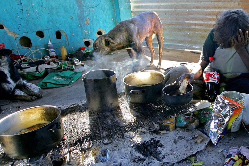 An Aboriginal woman prepares food in the squalid conditions of a Central Australian town camp.