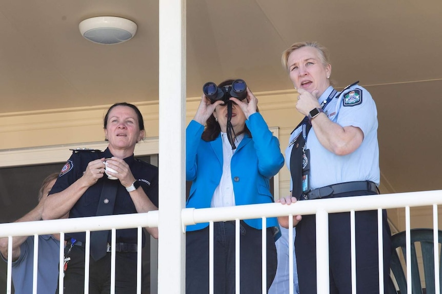 Ms Palaszczuk uses a pair of binoculars to inspect damage to the Peregian Beach area during a visit to Peregian Springs