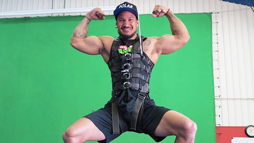 Gold Coast actor Johann Ofner flexes his muscles while hanging from a harness