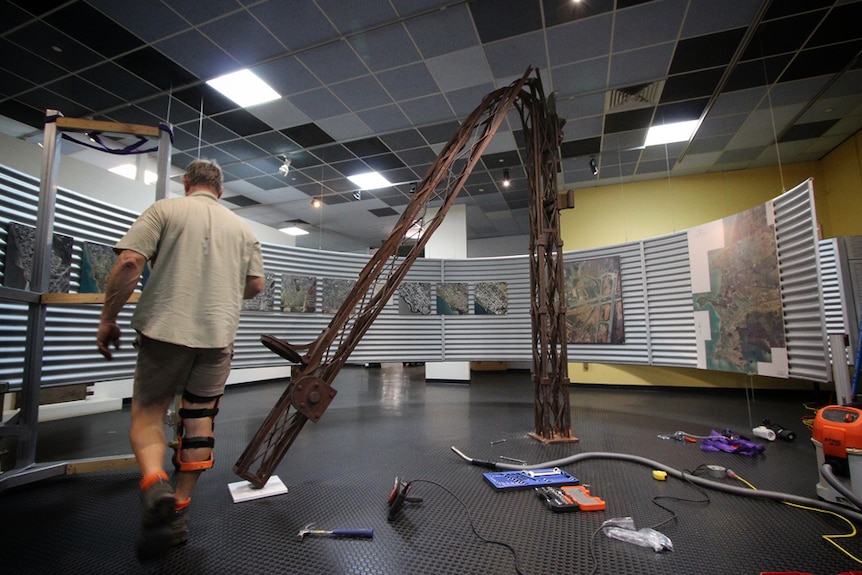 A worker installs a bent signal tower at an exhibition at the Museum & Art Gallery of the NT.