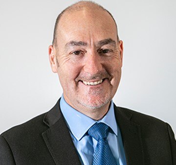 A man smiling in a suit and tie 