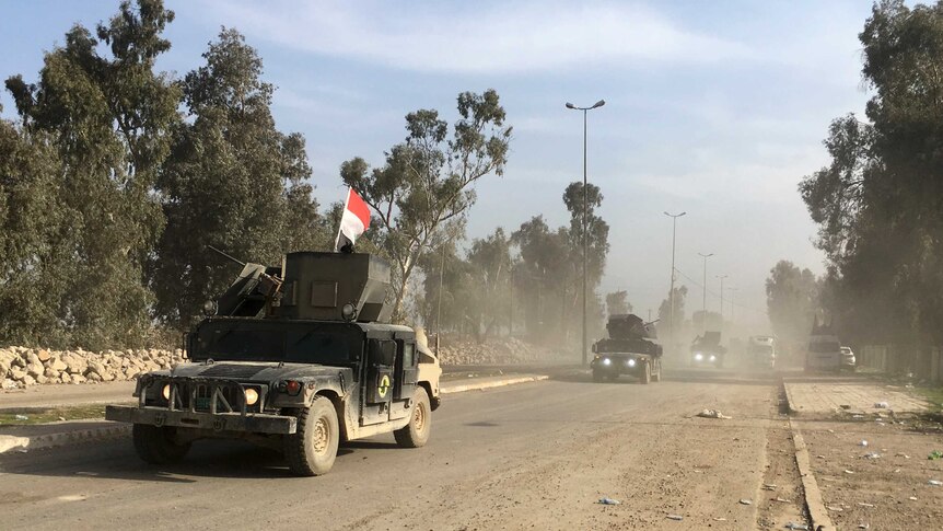 A column of Iraqi defence force units drives along a road in western Mosul.