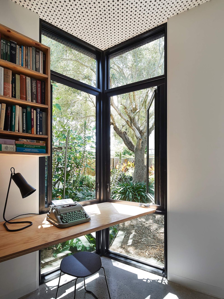 A typewriter and lamp sit on a desk.