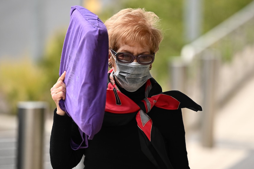 Melissa Caddick's mother Barbara Grimley holds a purple cushion next to her head