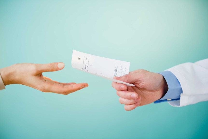 Close up of doctor's hand giving prescription to patient.