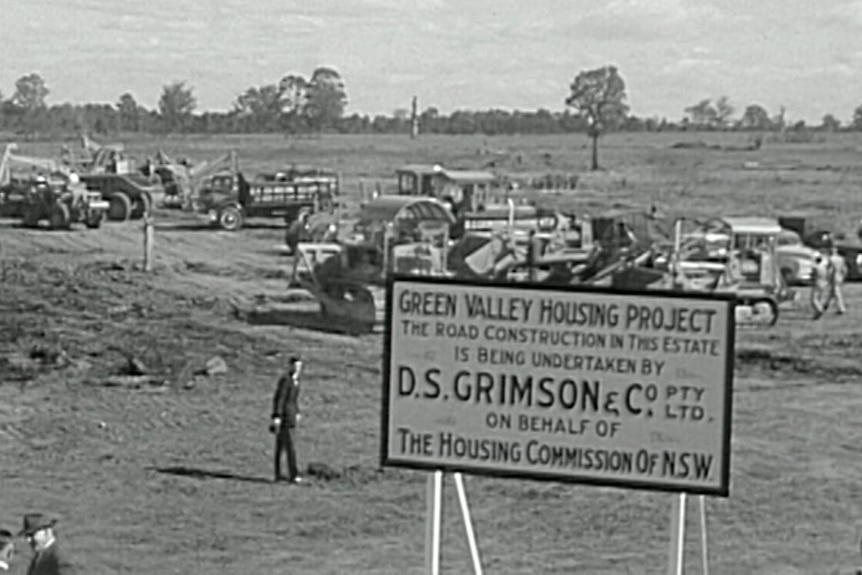 black and white image of trucks turning soil with a sign of green valley