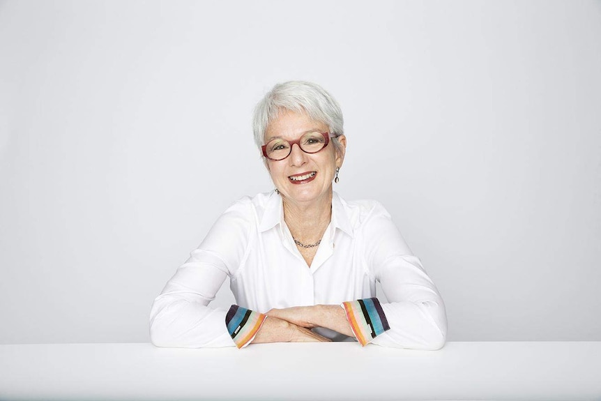 A woman in a white collared shirt smiles