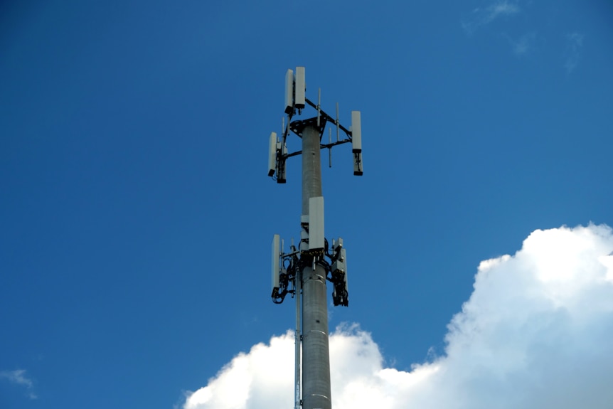 A mobile tower stands tall in the sky, clouds in the background