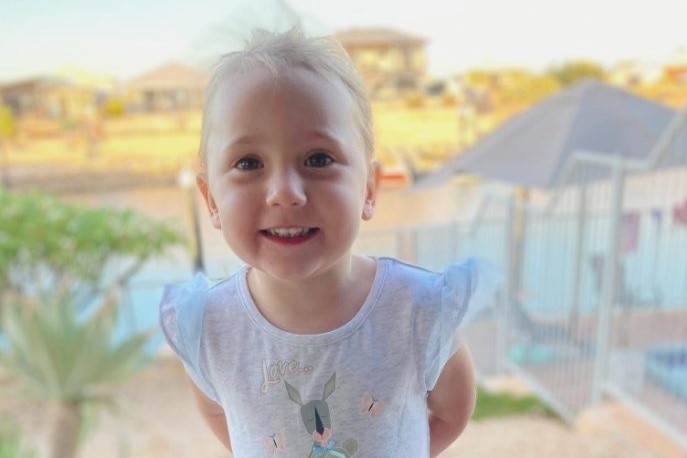 A little girl smiling and wearing a blue dress