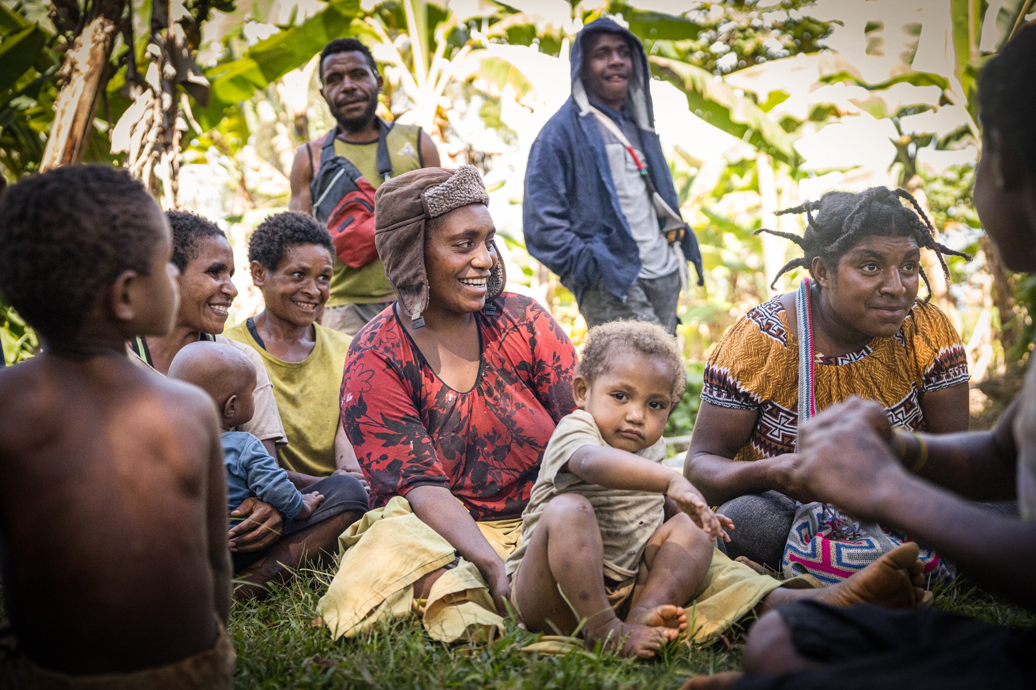A close up of a woman holding a child on her lap surrounded by smiling women and children.