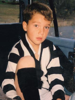 Little boy in a Collingwood Jumper looking at camera.