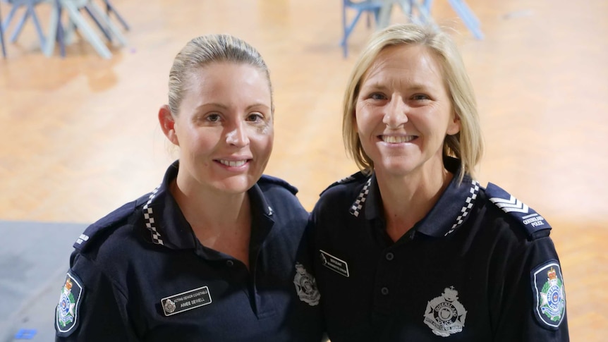 Two female police officers in uniform smiling at the camera.