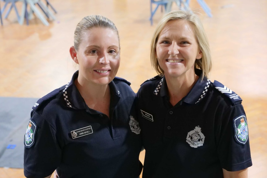 Two female police officers in uniform smiling at the camera.