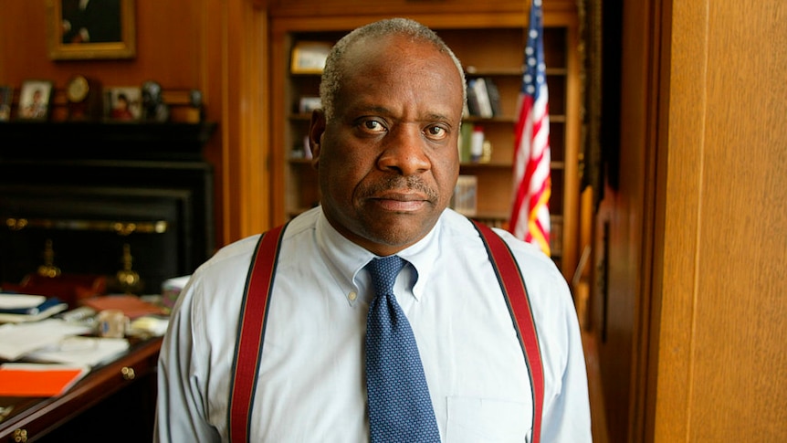 A younger Clarence Thomas poses for a photograph in his office