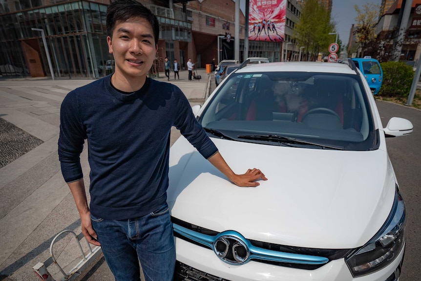 Kelvin Feng leans against the hood of his new electric vehicle