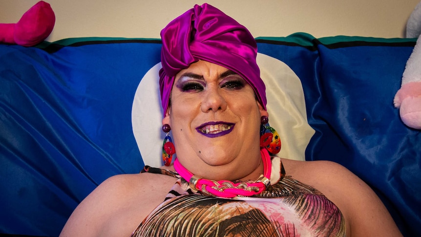 Drag queen MadB is sitting on their couch after getting into drag.