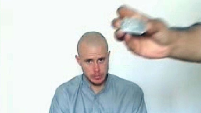 Private Bowe Bergdahl watches as one of his Taliban captors displays his identity tag to the camera.