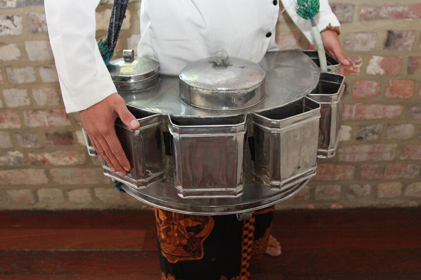 A shiny, silver set of pans that is worn around the waist by street vendors.