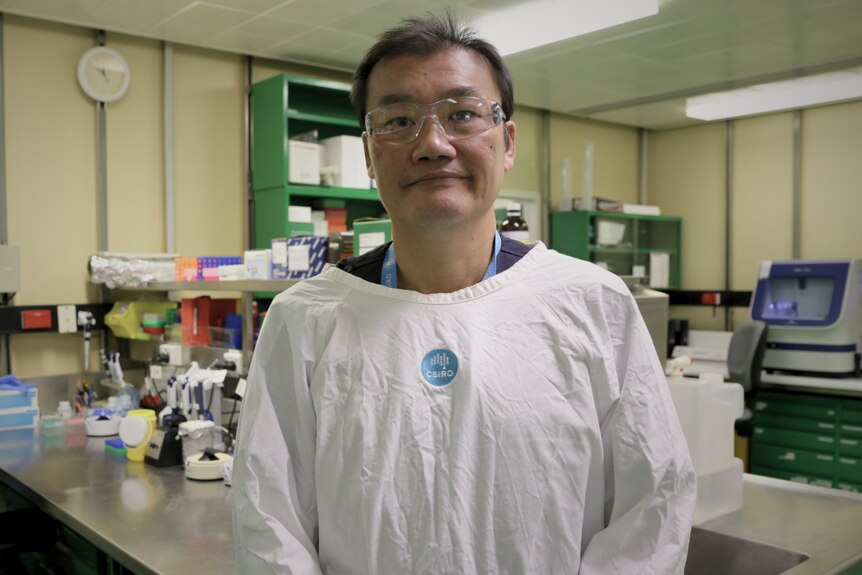 Dr Frank Wong in a lab coat standing inside a laboratory. 