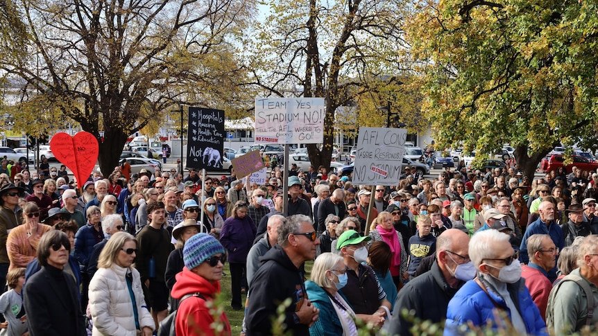 A crowd of people holds signs at a rally