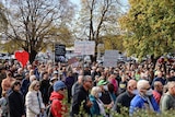 A crowd of people holds signs at a rally