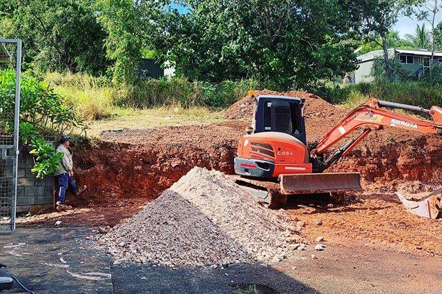 A pile of white ochre in the middle of an excavation pit, with an earth mover nearby