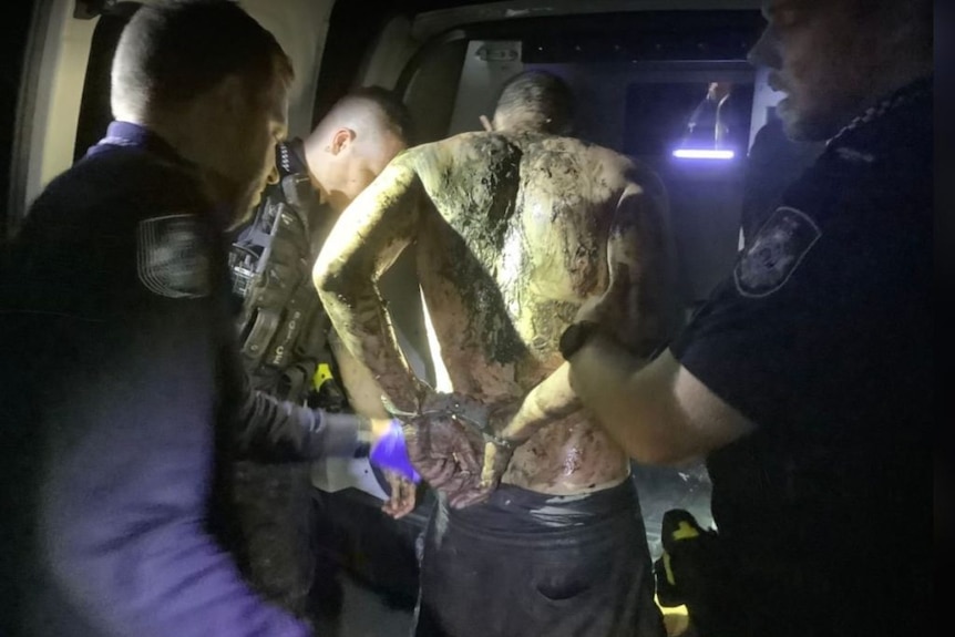 The offender covered in mud with his hands cuffed.