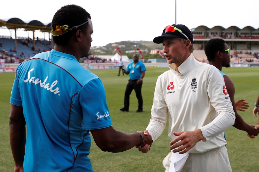 Joe Root shakes hands and speaks with Shannon Gabriel, who has his back to the camera.