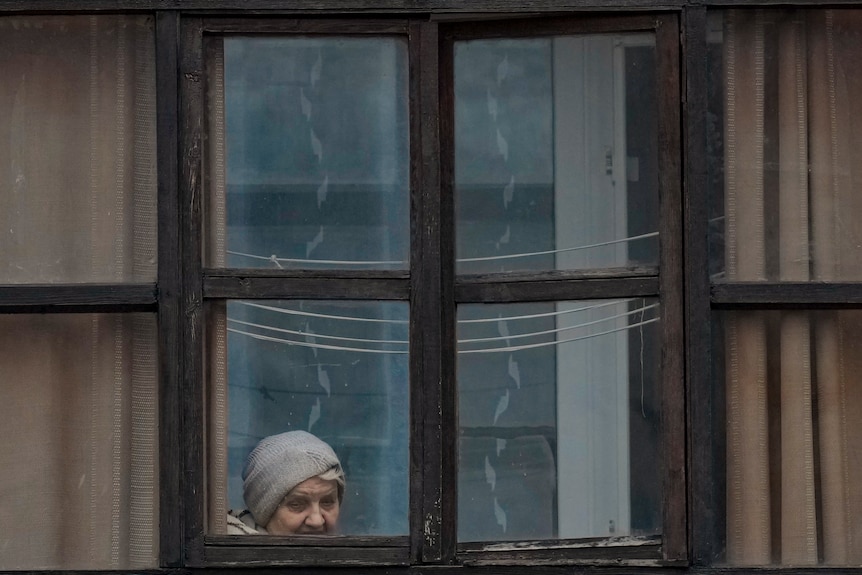 A woman looks out of the window of a balcony in Luhansk