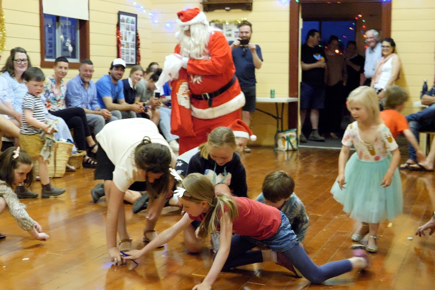 Santa throws lollies while kids scramble to pick them up