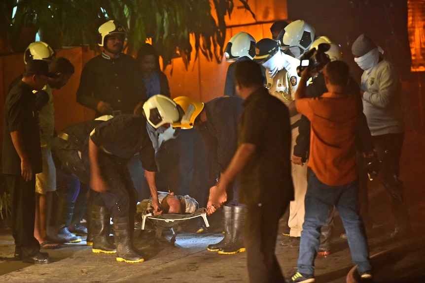 Fire officials carry an injured person from the fire at the Mumbai restaurant.