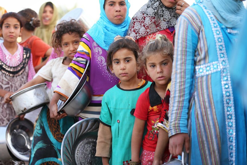 Children waiting in line for food at Baharka camp in Iraq