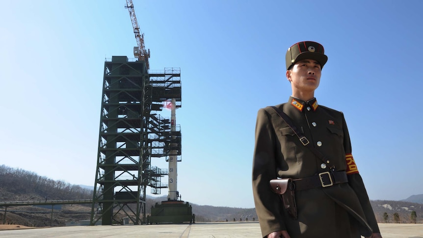 A North Korean soldier stands guard in front of an Unha-3 rocket