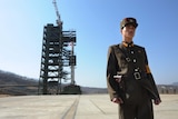 A North Korean soldier stands guard in front of an Unha-3 rocket