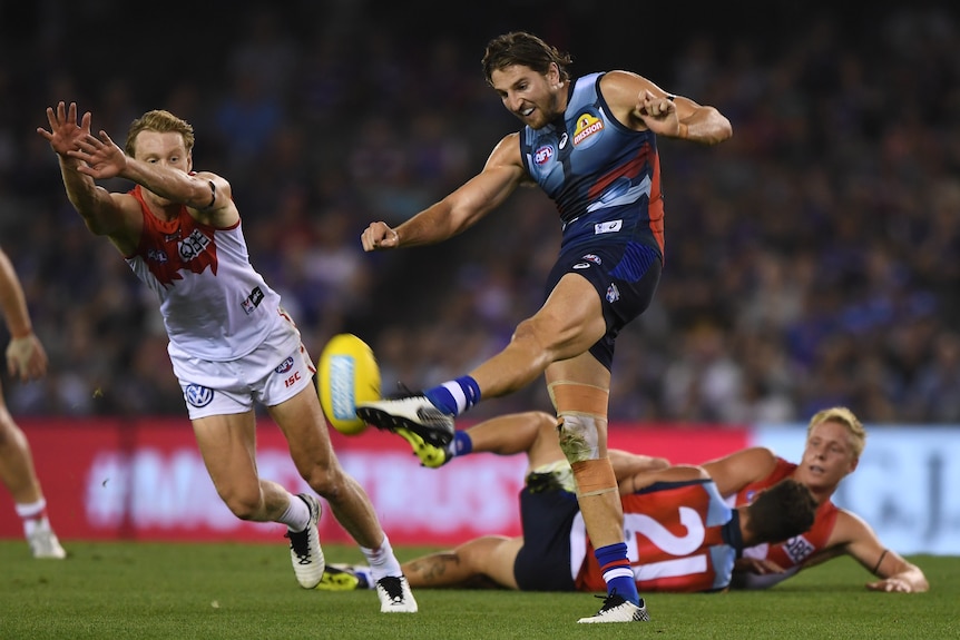Western Bulldogs' Marcus Bontempelli makes contact with the ball as he kicks for goal as a Swans defender scrambles to block