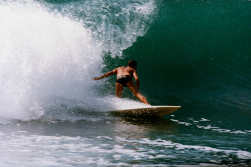 Picture of a man in bathers surfing a large wave