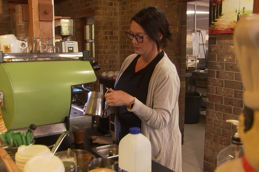 A woman makes a coffee at a cafe.