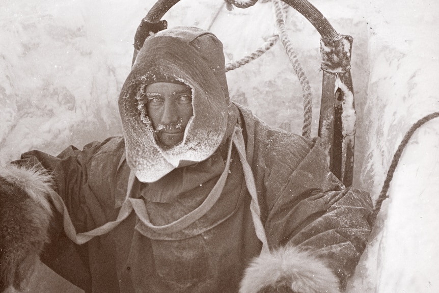 A man stands in a hole in the ice in Antarctica during a British expedition.