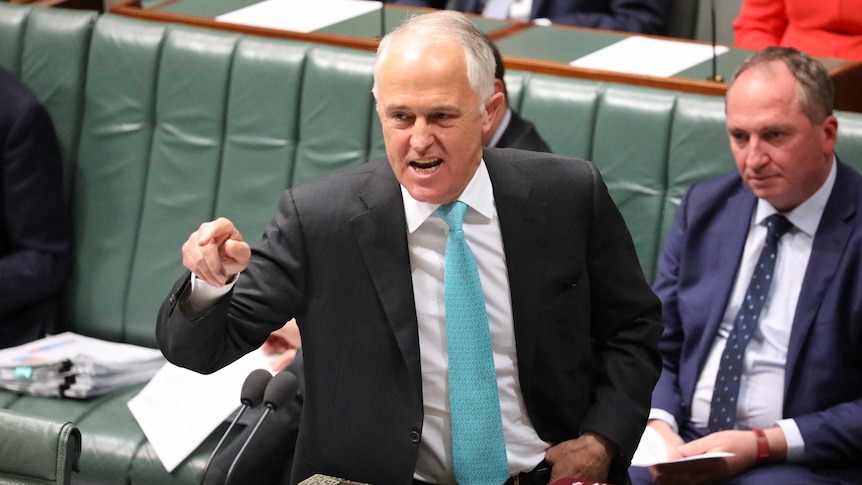 Malcolm Turnbull, looking angry, points his finger towards the Opposition during Question Time. Behind him is Barnaby Joyce.